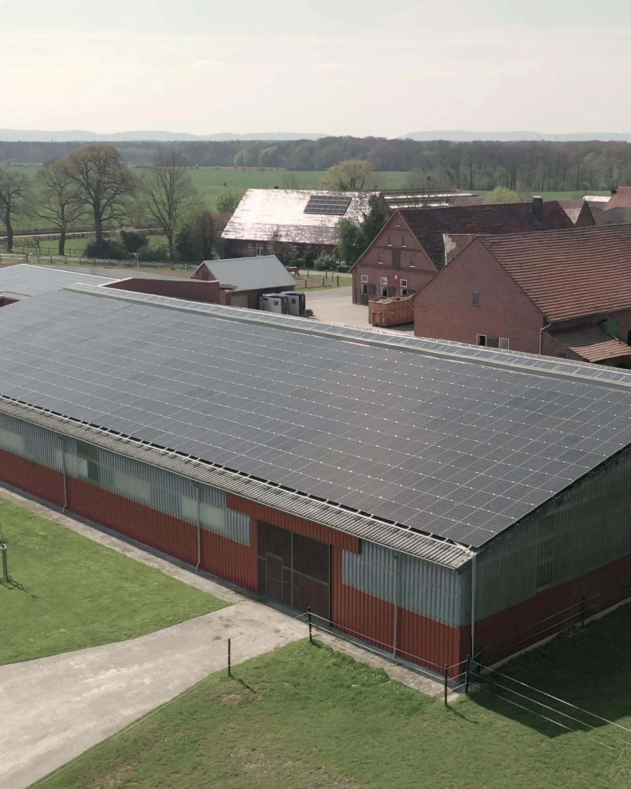 Luftaufnahme der Halle in Petershagen, das Dach vollflächig mit Photovoltaik belegt, dahinter der Hof